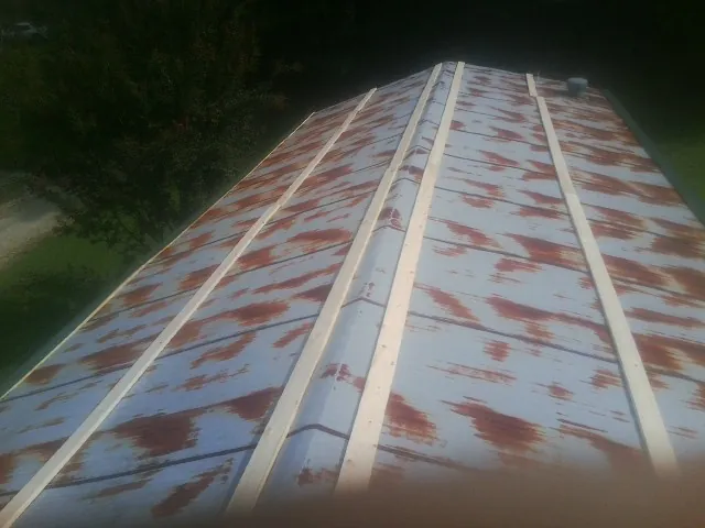 Rusted metal roof panels with new wood purlins before replacement — Storm Damage Roof Repair in Raymore by Roofing Brothers