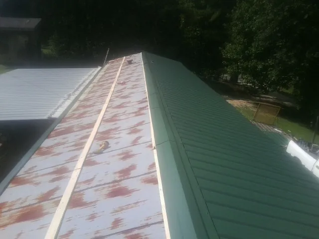 Old rusted panels beside newly installed green metal roofing — Wind Damage Roof Repair by Roofing Brothers in Raymore