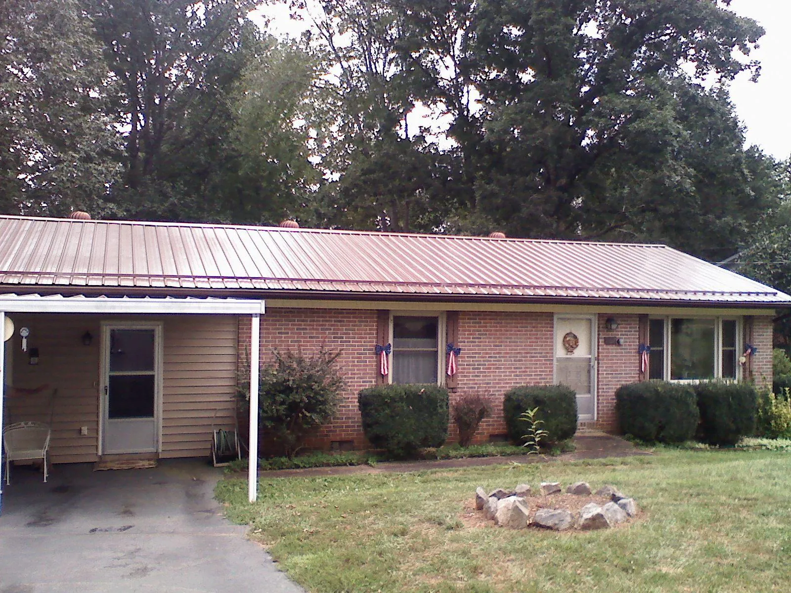 Bronze metal roof and carport on a brick ranch home — Roof Repair work by our crew in Raymore