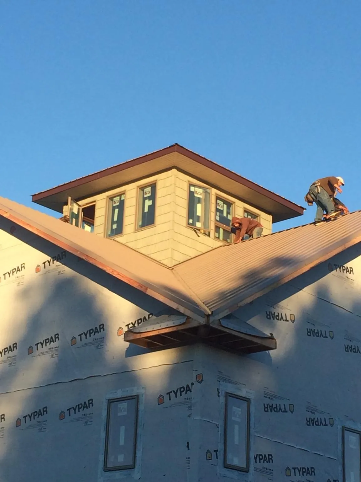 Roofers working around a rooftop cupola on a new metal roof at sunset — Roof Waterproofing in Raymore by Roofing Brothers